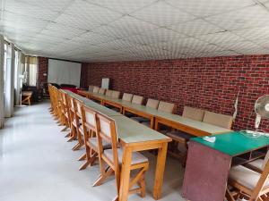 a row of tables and chairs in a room with a brick wall at Dhulikhel Training center in Dhulikhel