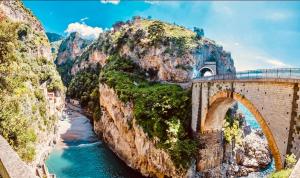 a bridge over a river next to a mountain at Grandmother's Attic in Furore