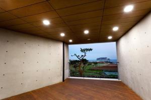 a room with a large window with a view of a tree at The BB's Jeju Resort in Seogwipo +9 photos