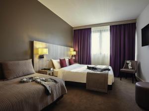 a hotel room with two beds and a chair at Mercure Versailles Paris Ouest in Versailles +50 photos