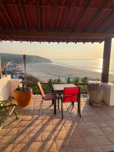eine Terrasse mit einem Tisch und zwei Stühlen und dem Meer in der Unterkunft Milky Way in San Miguel del Puerto