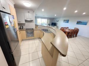 a kitchen with a counter with a sink and a refrigerator at Jubilee Apartment 04 - Bring your own linen in South West Rocks