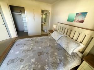 a bedroom with a bed with a blanket and pillows at Jubilee Apartment 04 - Bring your own linen in South West Rocks +9 photos