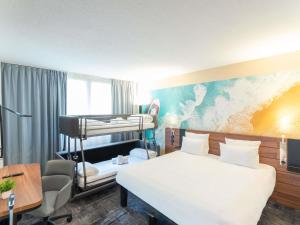 a hotel room with a bed and a desk at Novotel Antibes Sophia Antipolis in Valbonne