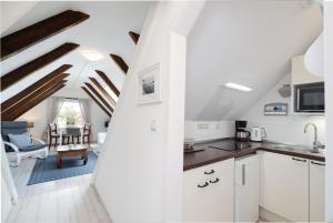a kitchen with white cabinets and a living room at Möhlenblick in Neustadt in Holstein