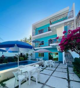 a villa with a swimming pool and tables and umbrellas at Casa Bugambilias 3 tercer piso in La Peñita de Jaltemba