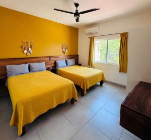 two beds in a room with yellow walls at Casa Bugambilias 3 tercer piso in La Peñita de Jaltemba