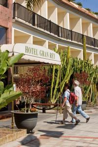 two people walking past a hotel grain ray sign at Hotel Gran Rey in Valle Gran Rey