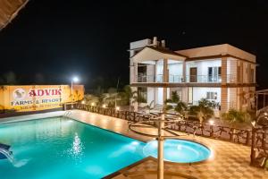a villa with a swimming pool at night at Advik Resort in Badlapur