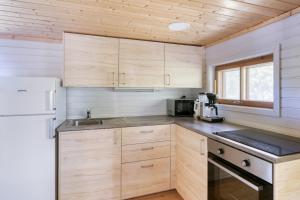a kitchen with wooden cabinets and a white refrigerator at Pinetree Cottages Sunny cabin in Pyhäranta