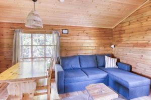 a living room with a blue couch and a table at Pinetree Cottages Sunny cabin in Pyhäranta