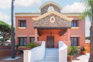 a pink house with stairs in front of it at Hotel Amapola La Barrosa in Novo Sancti Petri