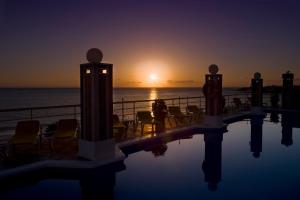 a swimming pool with chairs and the ocean at sunset at Hotel Gran Rey in Valle Gran Rey
