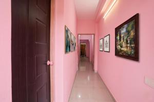 a hallway with pink walls and pictures on the walls at FabHotel Shadowline in Goa