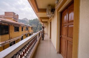 a woman standing on the balcony of a building at FabHotel Shadowline in Goa