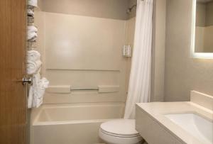 a bathroom with a toilet and a tub and a sink at Super 8 by Wyndham Warrenton in Warrenton +28 photos