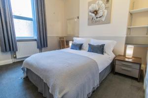 a bedroom with a bed with blue pillows and a window at Free Parking, Entire 8 Ensuite Bedroom Townhouse, Fully Equipped Kitchen, Dining Room & Lounge, Perfect for Family Gatherings, Long Term Contractor, Relocation, etc Stays, 15 mins to Nissan, 20 mins to Sunderland & Newcastle, See our Site for Assurance in South Shields