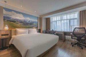 a bedroom with a large white bed and a desk at Atour Hotel (Urumqi Renmin Cinema) in Ürümqi