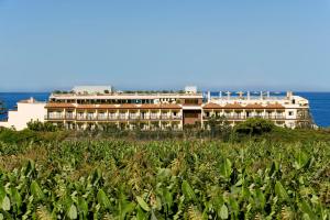 a large building on top of a hill next to the ocean at Hotel Gran Rey in Valle Gran Rey