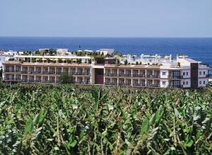 a large building with the ocean in the background at Hotel Gran Rey in Valle Gran Rey