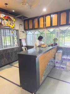 a woman sitting at a counter in a restaurant at Hotel Shree Jay Amba Deluxe in Jaisingpur