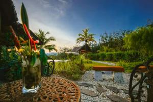 a table with a vase of flowers and a bench at Romantic Tropical Retreat with Sunset & Rice Field Views in Kuah