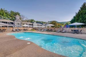 a swimming pool with chairs and tables and a building at The Green Granite North Conway, an Ascend Collection Hotel in North Conway