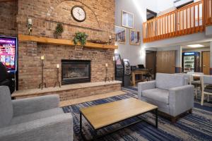 a lobby with a brick fireplace with a clock on the wall at AmericInn by Wyndham Baldwin in Baldwin