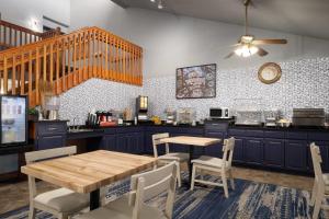 a kitchen with blue cabinets and a wooden table and chairs at AmericInn by Wyndham Baldwin in Baldwin