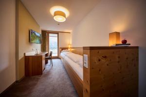 a hotel room with a bed and a desk and a sink at Das Kronthaler - Adults only in Achenkirch