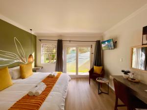 a bedroom with a bed with a desk and a window at Olive Tree Boutique Guesthouse in Swakopmund
