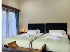 two beds in a hotel room with towels on them at Noble Bali Diving Resort Tulamben in Tulamben