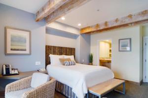 a bedroom with a large white bed and a chair at Cypress Inn on Miramar Beach in Half Moon Bay