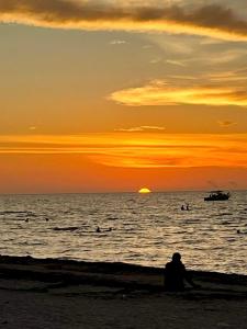 a person sitting on the beach watching the sunset at Departamento chichan nah in Progreso