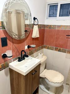 a bathroom with a sink and a toilet and a mirror at Departamento chichan nah in Progreso +21 photos