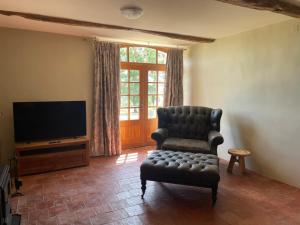 a living room with a chair and a television at Château d'Arcamont in Roquelaure