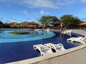 a swimming pool with white lounge chairs in a resort at Flat Hotel Canarius Gravatá in Gravatá