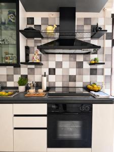 a kitchen with a black and white tiled wall at Avola Garden Apartment near Pantanello Beach in Avola