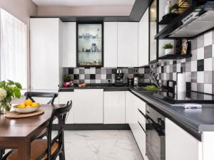 a kitchen with white cabinets and a wooden table at Avola Garden Apartment near Pantanello Beach in Avola