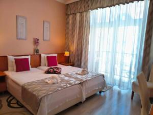 a bedroom with a large bed and a large window at Hotel Isabell Győr in Győr