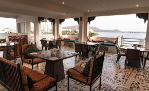 a restaurant with tables and chairs and a view of the water at hotel sargam sadan in Jāmb