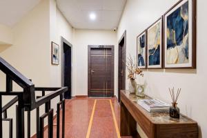 a hallway with a table and a staircase with paintings at FabHotel Shivangan in Vrindāvan
