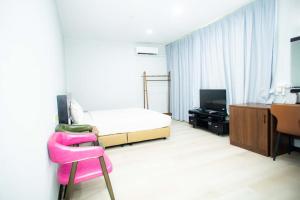 a bedroom with a bed and a desk and a pink chair at Prince Hotel in Tawau