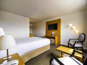 a hotel room with a bed and a desk and a tv at Mercure Bordeaux Lac in Bordeaux