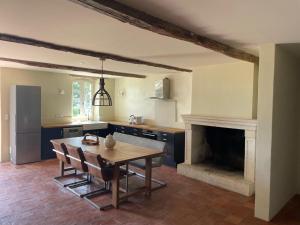 a kitchen with a wooden table and a fireplace at Château d'Arcamont in Roquelaure