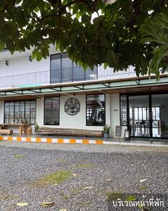 a white building with a clock on the side of it at Mei Nai Home เมย นาย โฮม in Ban Sakat Nua