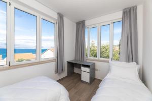 two beds in a room with large windows at APARTMENT MARCELA SUTIVAN - large two-bedroom apartment with two bathrooms - excellent location right by the town center and the beach - parking space provided - panoramic view of the sea and the town in Sutivan