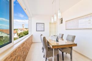 a dining room with a table and chairs and a window at APARTMENT MARCELA SUTIVAN - large two-bedroom apartment with two bathrooms - excellent location right by the town center and the beach - parking space provided - panoramic view of the sea and the town in Sutivan