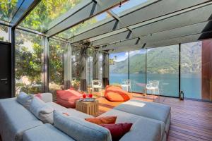a living room with a couch and large glass windows at Maison Sur l'Eau - Lugano Villa with View Terrace in Paradiso