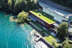a house with a green roof on top of a river at Maison Sur l'Eau - Lugano Villa with View Terrace in Paradiso